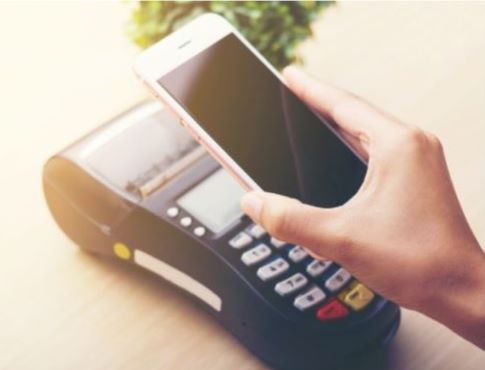 Image of someone holding their mobile phone over a payment terminal
