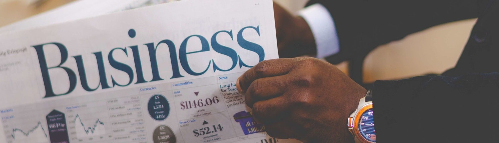 a pair hands holding the business section of the newspaper