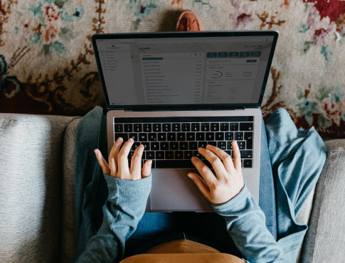 Woman sitting on her couch using her computer to do online banking