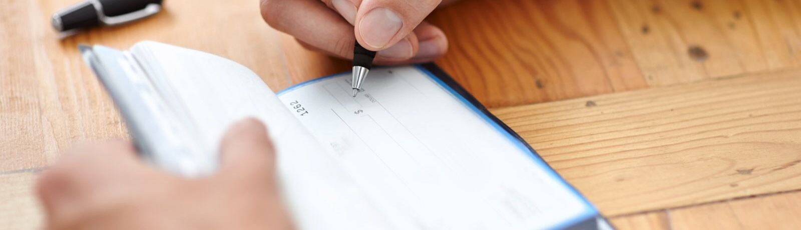 Image of someone writing a check from a check book