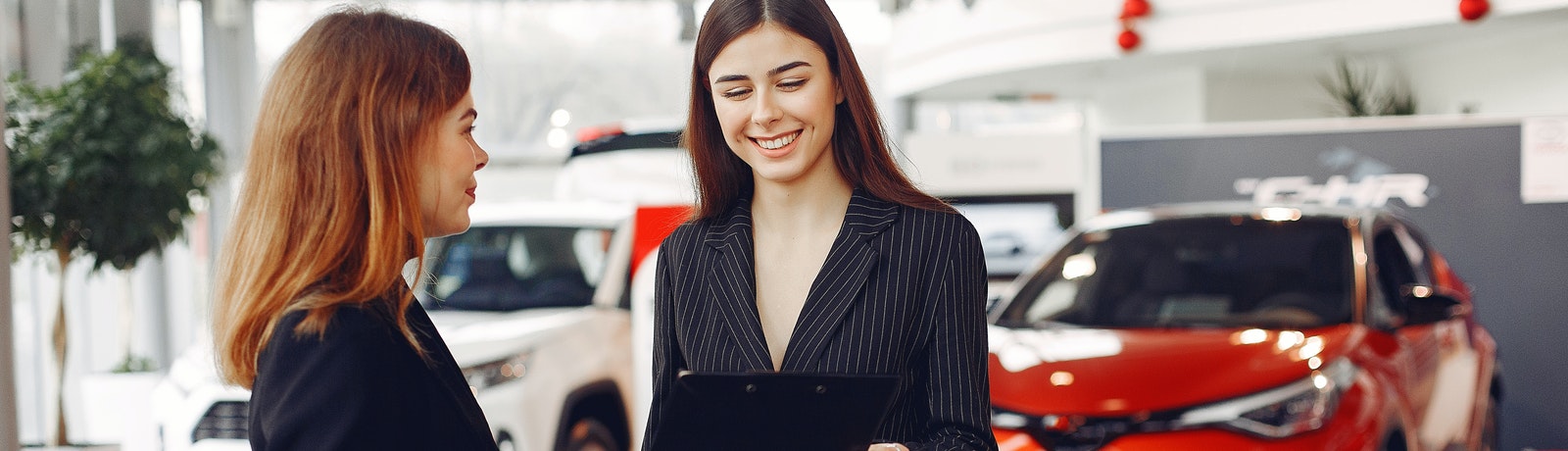 two people at a card dealership in front of a car