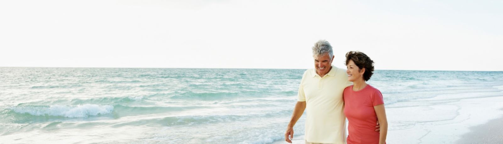 Image of a couple walking down the beach smiling