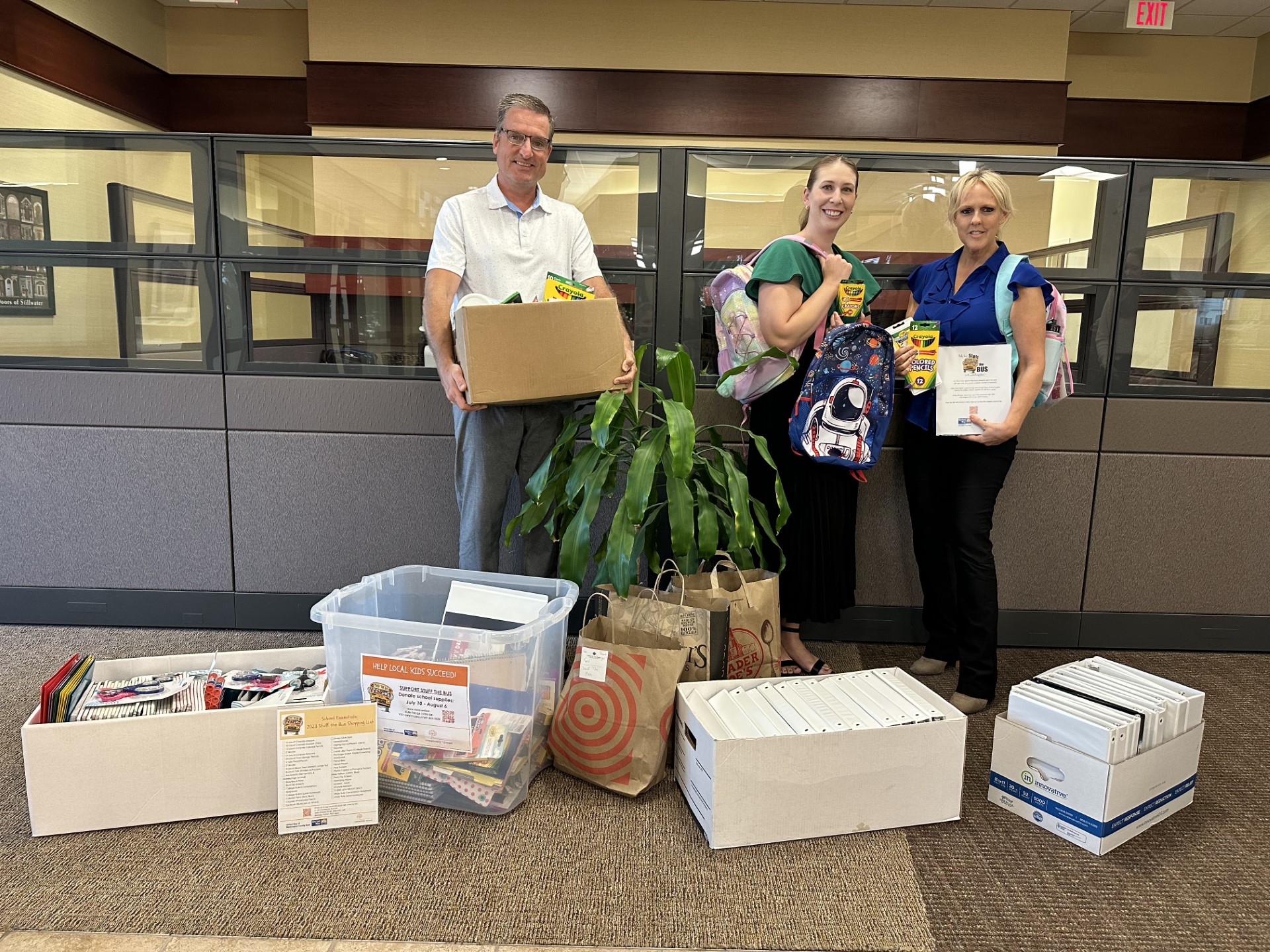Image of three of our employees packing up donations for the Stuff the Bus campaign
