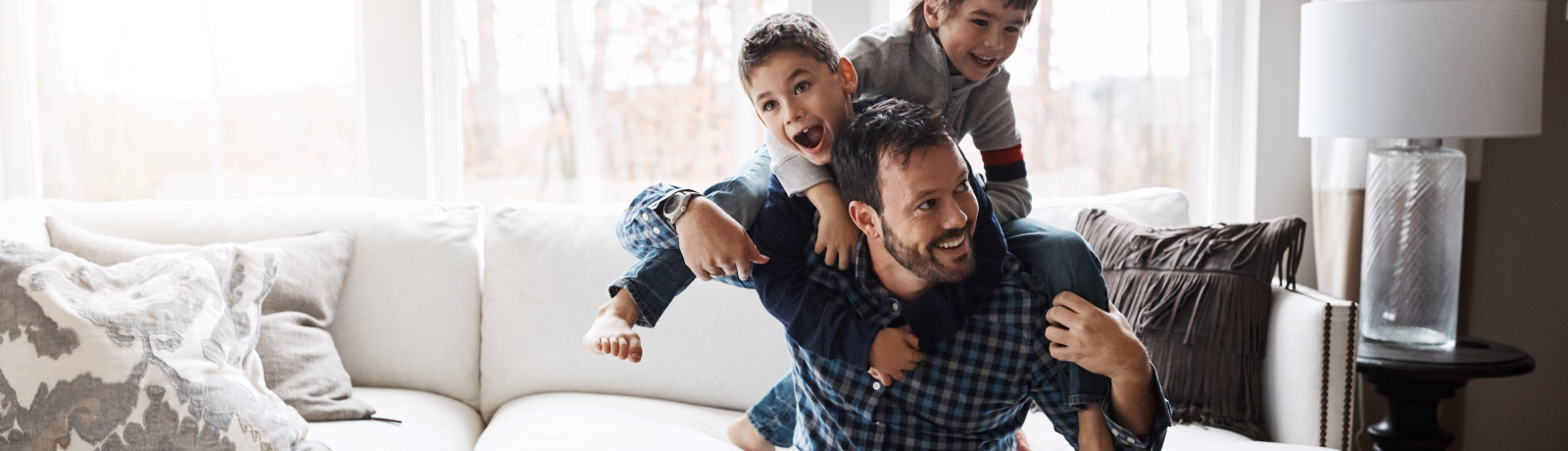 Man on couch with two children climbing on his back